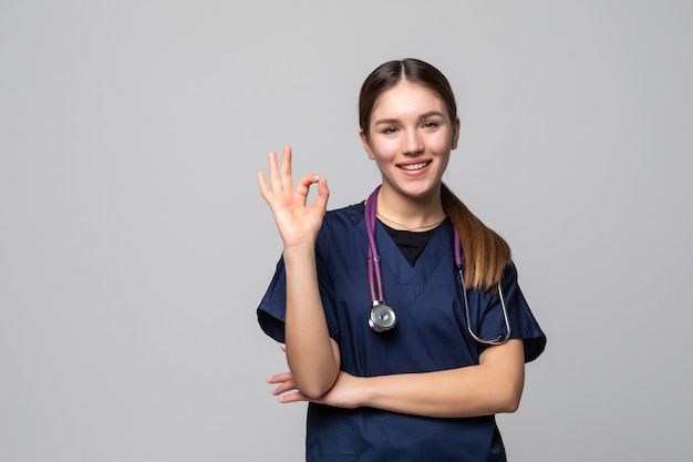 Gelukkig lachende vrouwelijke arts met goed gebaar, geïsoleerd op wit