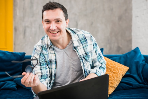 Gratis foto gelukkig mannetje dat aan laptop in woonkamer werkt