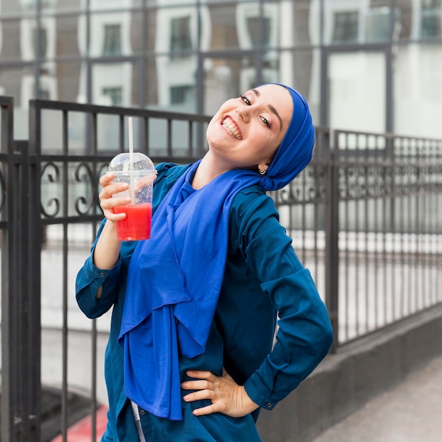 Gelukkig meisje dat een hijab draagt en een smoothie houdt