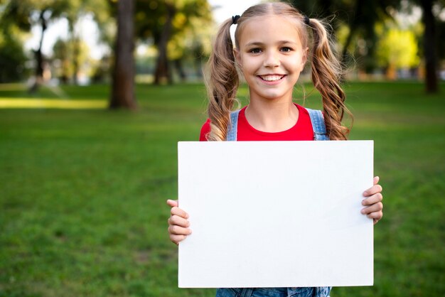 Gelukkig meisje dat lege banner in haar hand houdt