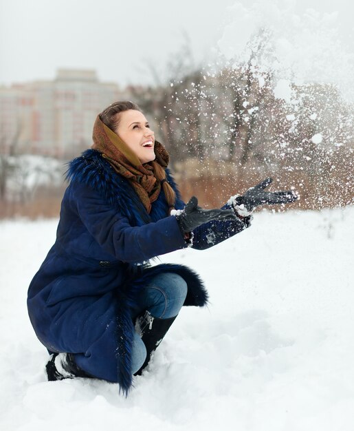 Gelukkig meisje dat sneeuwvlokken werpt