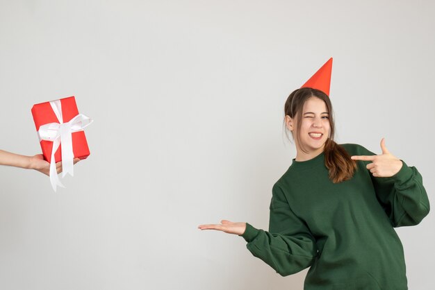 gelukkig meisje met feestmuts wijzend met vinger menselijke hand met geschenk op wit