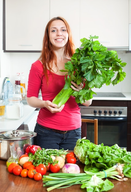 Gelukkig meisje met verse groenten en greens in de keuken