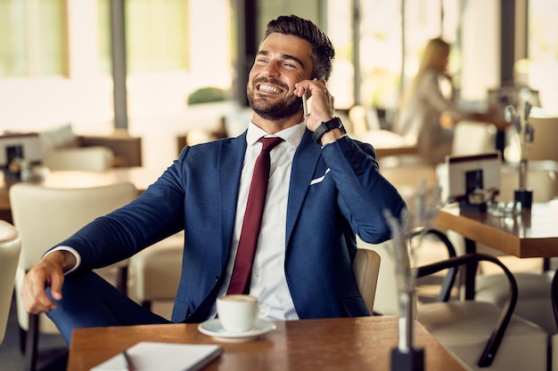 Gelukkig midden volwassen zakenman met behulp van mobiele telefoon tijdens een koffiepauze in een café