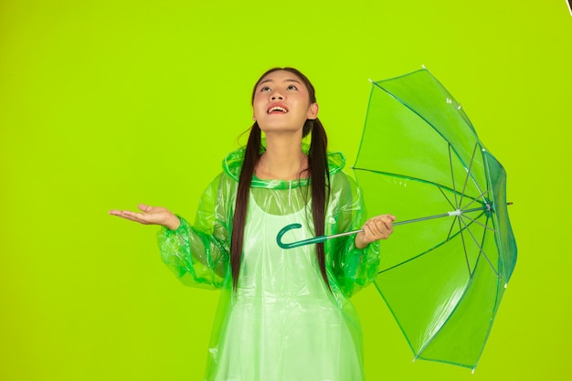 gelukkig mooi meisje, groene kleding, paraplu en jas, regenachtige dag dragen.