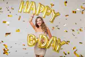 Gratis foto gelukkig mooie vrouw viert verjaardag in gouden confetti