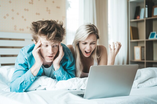 Gelukkig paar dat laptop computer op het bed met behulp van