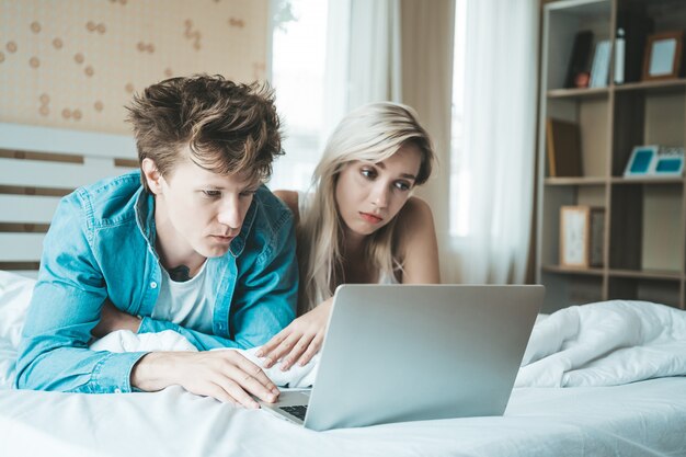 Gelukkig paar dat laptop computer op het bed met behulp van