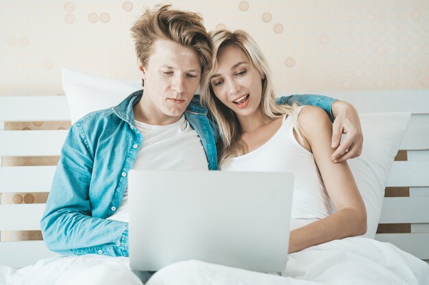 Gelukkig paar dat laptop computer op het bed met behulp van