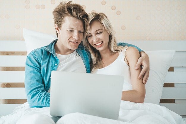 Gelukkig paar dat laptop computer op het bed met behulp van