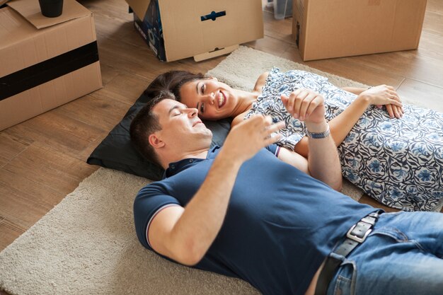 Gelukkig paar dat op de vloer ligt na het intrekken. Vrouw en man lachend