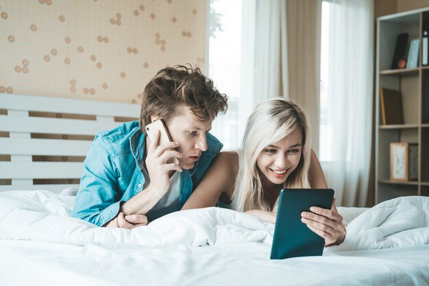 Gelukkig paar dat tabletcomputer op het bed met behulp van