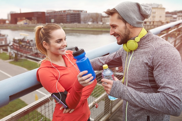 Gratis foto gelukkig paar drinkwater na het sporten