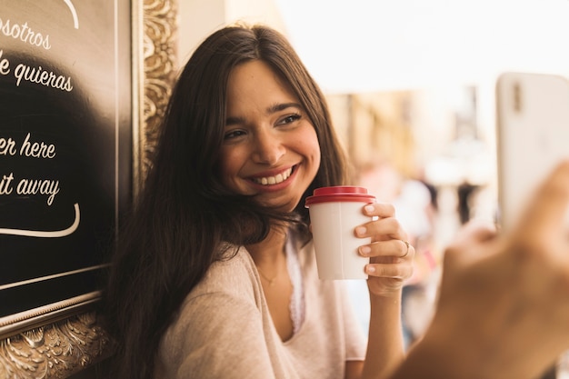 Gelukkig portret van een meisje die meeneem koffiekopje houden