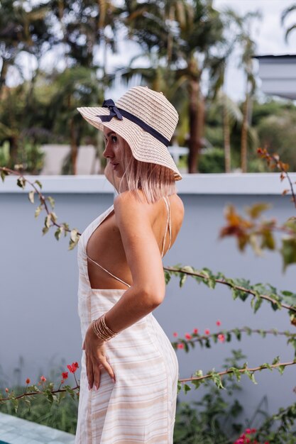 Gelukkig schattig romantisch blanke vrouw in zomer elegante witte open rug jurk, strooien hoed