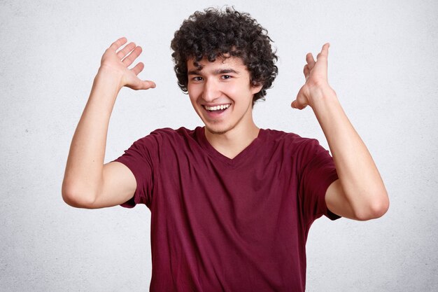 Gelukkig tiener met krullend haar, gekleed in casual t-shirt