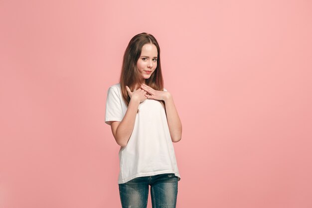 Gelukkig tienermeisje staan, glimlachend geïsoleerd op trendy roze studio