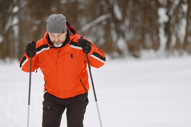 Gelukkig volwassen man in winter park. Senior activewear trekking in het bos ter vrije besteding