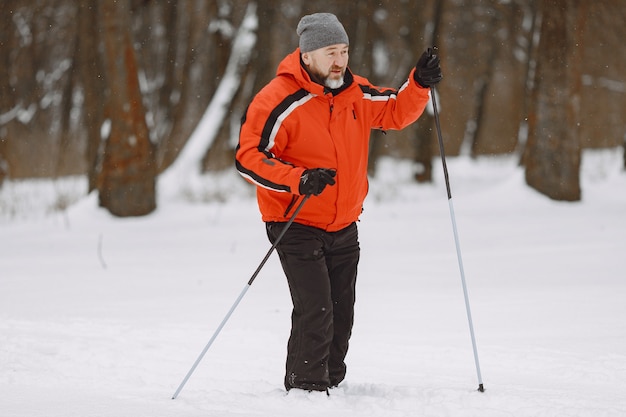 Gelukkig volwassen man in winter park. Senior activewear trekking in het bos ter vrije besteding