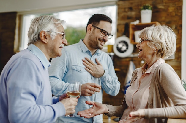 Gelukkig volwassen stel dat plezier heeft tijdens het communiceren met hun volwassen zoon in de keuken