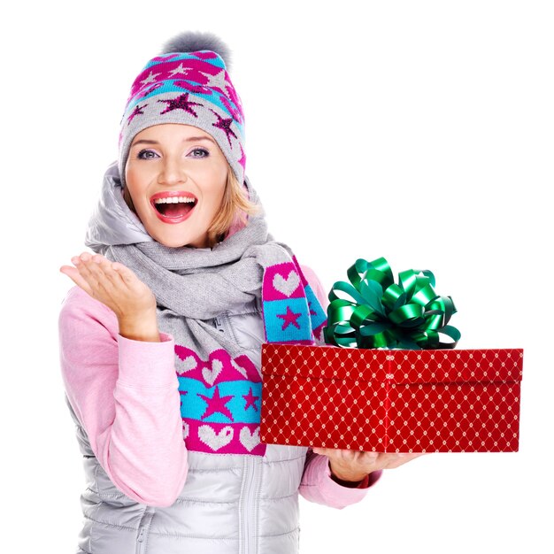 gelukkig volwassen vrouw met een cadeau in een winter bovenkleding op wit wordt geïsoleerd