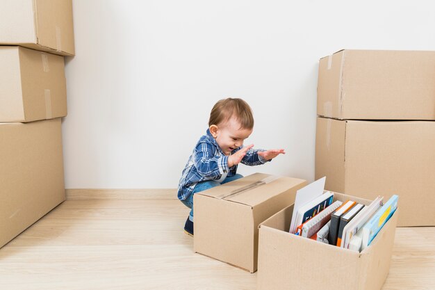 Gelukkig weinig babyjongen die met kartondozen bij nieuw huis speelt