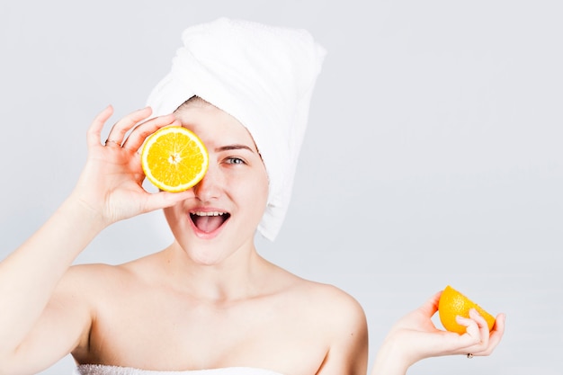 Gelukkig wijfje in handdoek met sinaasappelen op het gezicht