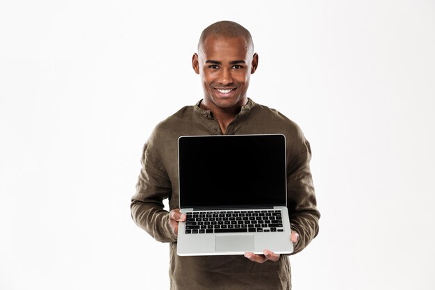 Gelukkige Afrikaanse mens die het lege laptop computerscherm en kijken toont