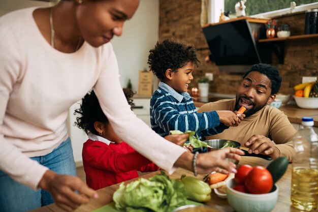 Gelukkige Afro-Amerikaanse familie die plezier heeft tijdens het bereiden van gezond voedsel in de keuken