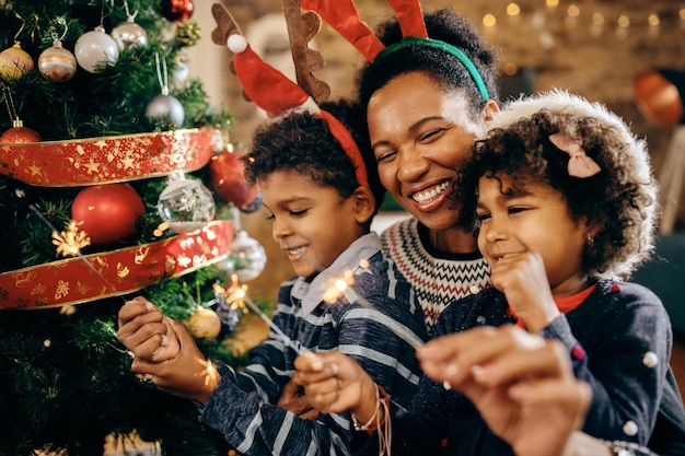 Gelukkige Afro-Amerikaanse familie die sterretjes gebruikt terwijl ze thuis Kerstmis vieren