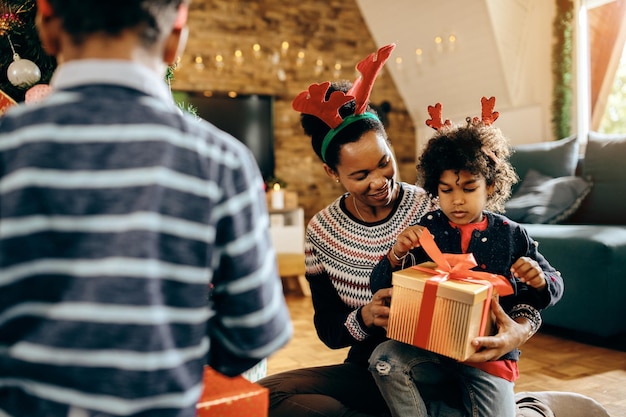 Gelukkige Afro-Amerikaanse moeder en dochter met kerstcadeau thuis