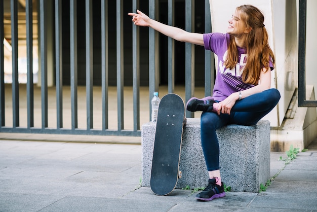 Gelukkige atletische vrouw zit met gekruiste been die aan iemand spreekt