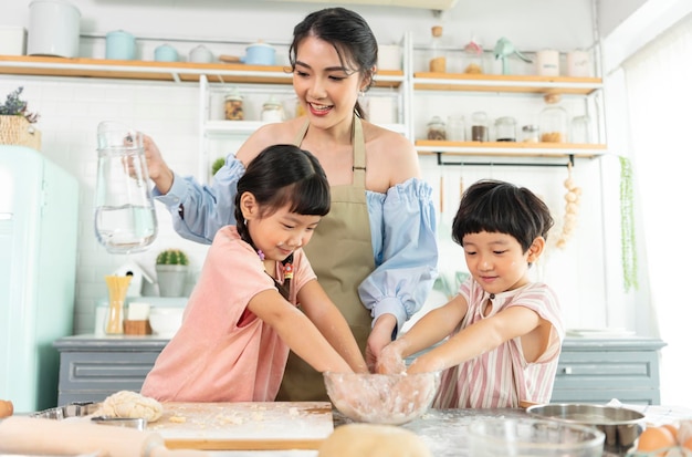 Gelukkige Aziatische familie die voorbereidingsdeeg maakt en koekjes thuis in keuken bakt Geniet van familie