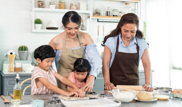 Gelukkige Aziatische familie die voorbereidingsdeeg maakt en thuis koekjes bakt in keuken