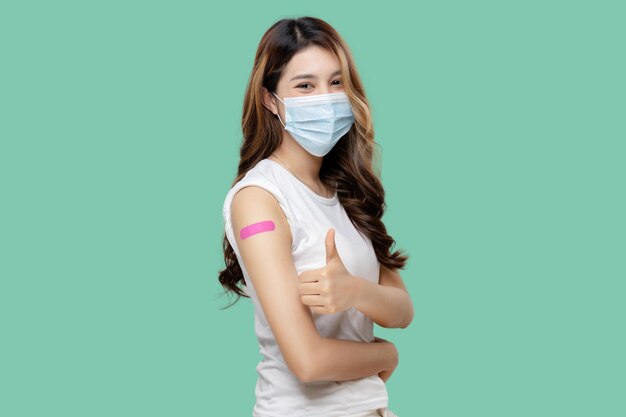 Gelukkige Aziatische vrouwen met gezichtsmasker voelen zich goed en tonen verband op arm na ontvangst van Covid19-vaccin duim omhoog