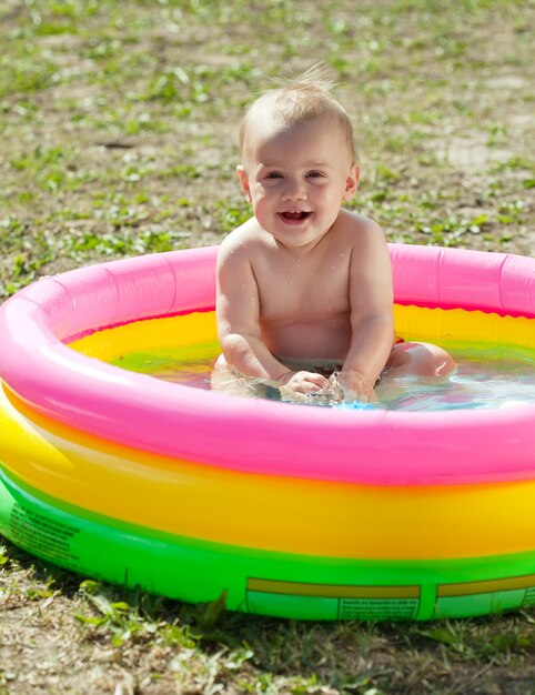 Gelukkige baby zwemmen in opblaasbaar zwembad