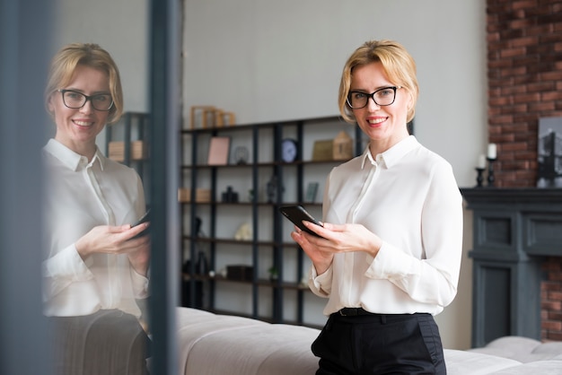 Gelukkige bedrijfsvrouw die smartphone gebruikt