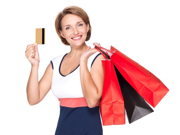 Gelukkige blanke vrouw met boodschappentassen en creditcard over witte ruimte
