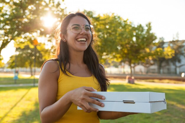 Gelukkige blije jonge vrouwen dragende pizza voor picknick