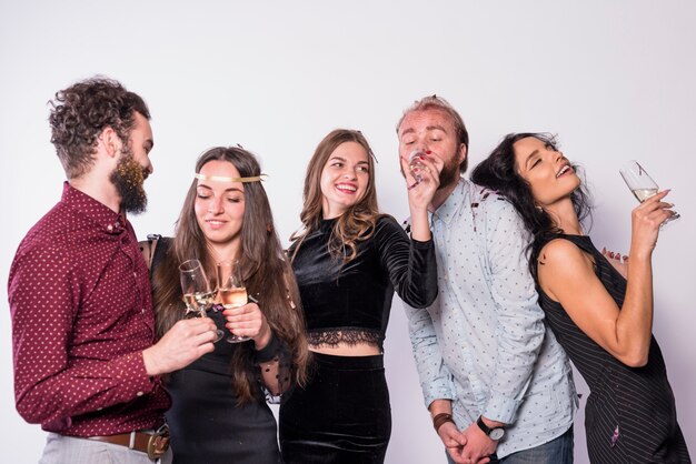 Gelukkige dames en jongens in avondkleding met glazen drankjes