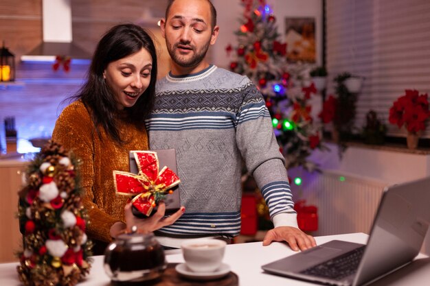 Gelukkige familie die een cadeau met lint erop toont tijdens online videogesprek