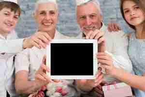 Gratis foto gelukkige familie die lege het scherm digitale tablet toont