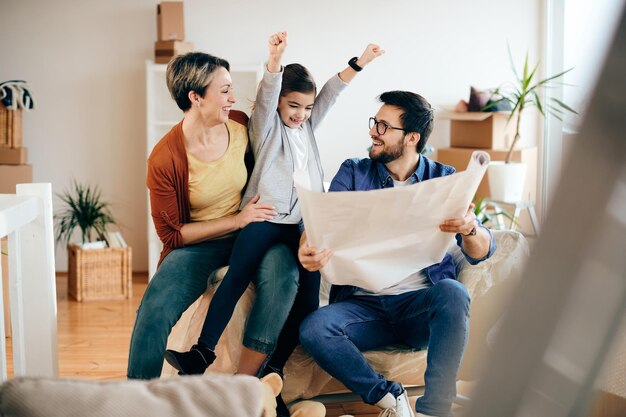 Gelukkige familie die plezier heeft tijdens het onderzoeken van de huisvestingsplannen van hun nieuwe huis
