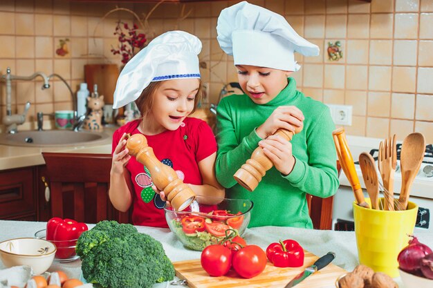 gelukkige familie grappige kinderen bereiden de verse groentesalade in de keuken voor