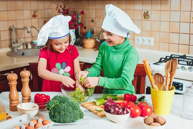 Gelukkige familie grappige kinderen bereiden de verse groentesalade in de keuken