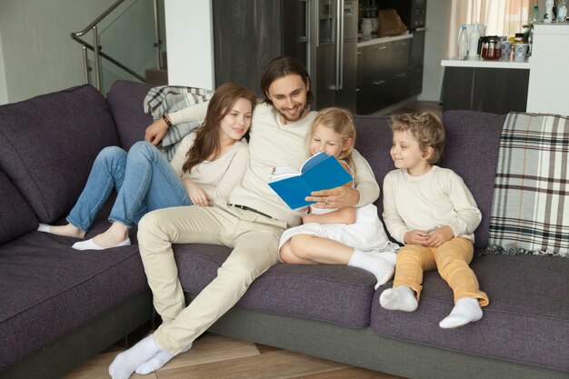 Gelukkige familie met kinderen die boek lezen die samen op bank zitten