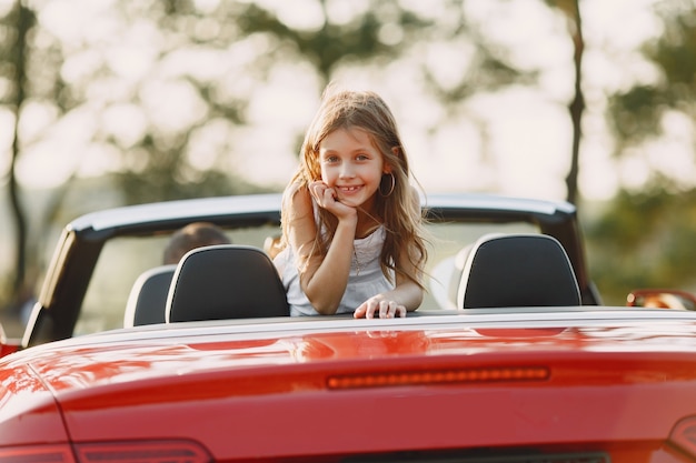 Gelukkige familie reist met de auto in de bergen. Mensen die plezier hebben in rode cabriolet. Zomer vakantie concept