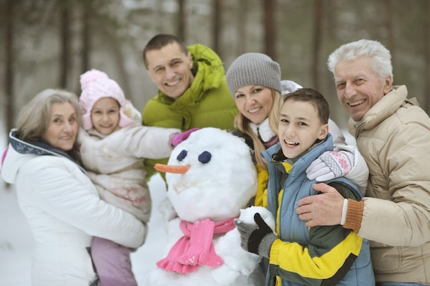 Gelukkige familie spelen in verse sneeuw en sneeuwpop bouwen op mooie zonnige winterdag buiten in de natuur