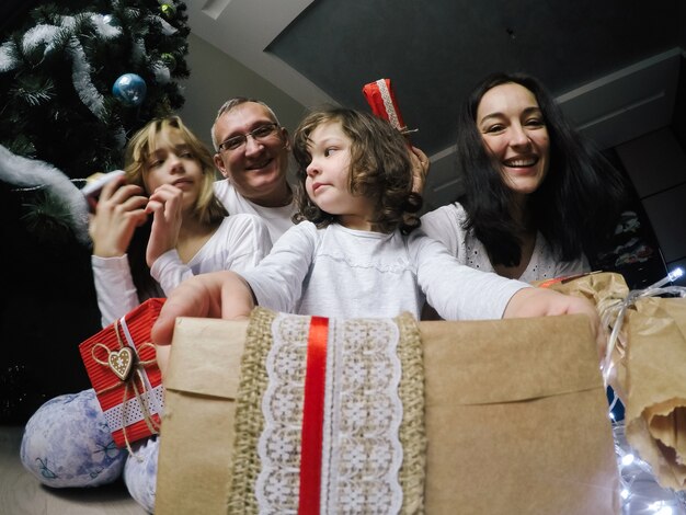 Gelukkige familie, zitten op een vloer in de buurt van een spar