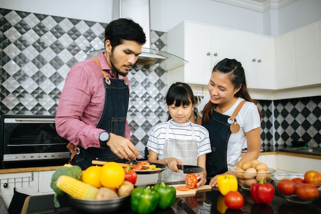 Gelukkige familiehulp die maaltijd samen in keuken thuis koken.